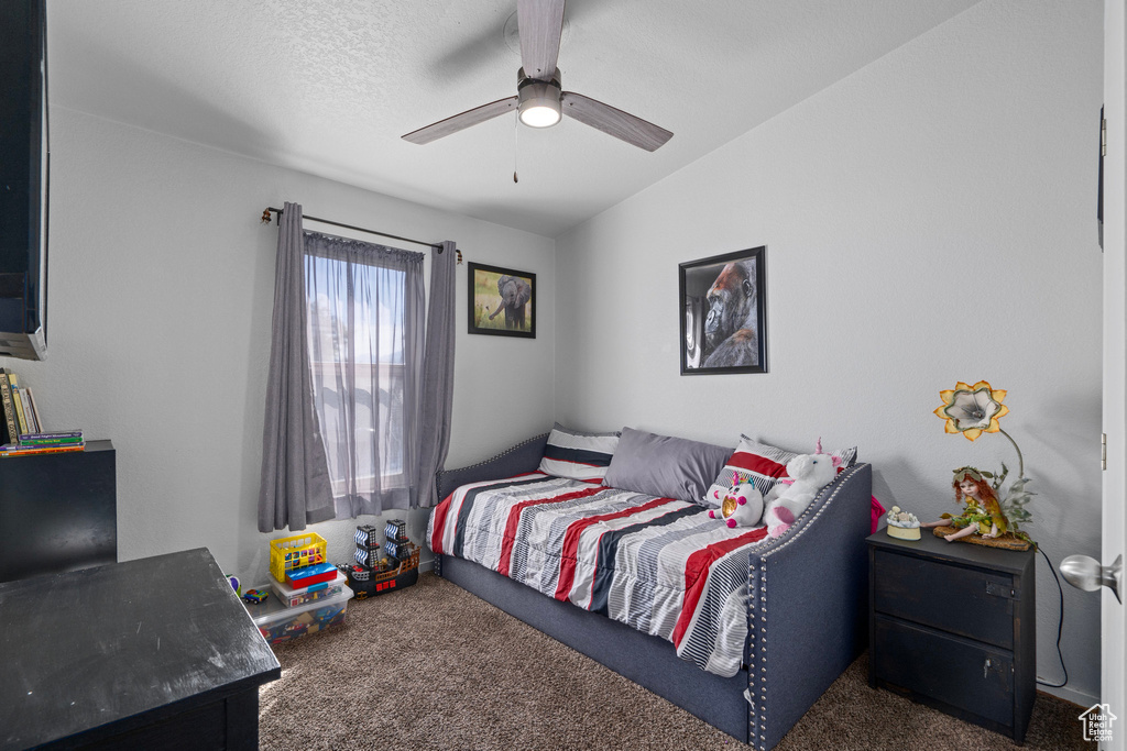 Bedroom with vaulted ceiling, ceiling fan, dark carpet, and a textured ceiling