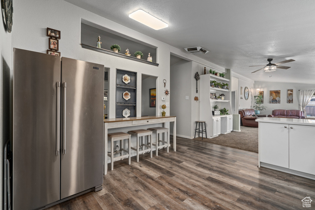 Kitchen featuring ceiling fan, white cabinets, a textured ceiling, stainless steel refrigerator, and dark hardwood / wood-style flooring