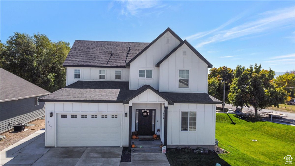 Modern farmhouse style home with a front lawn, central AC unit, and a garage