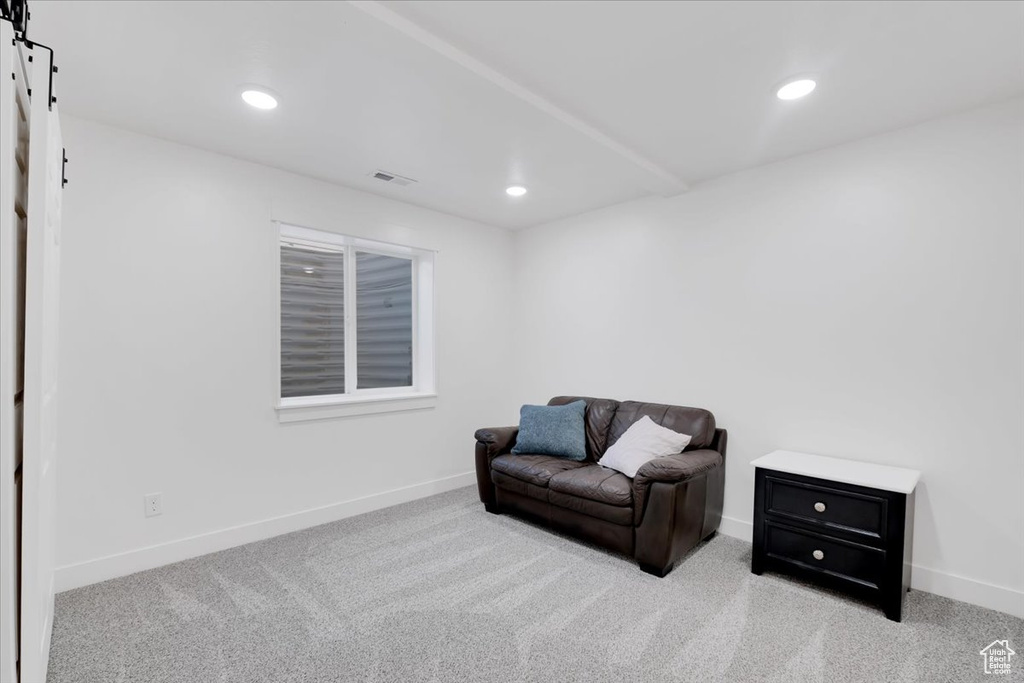 Living area with a barn door and light colored carpet