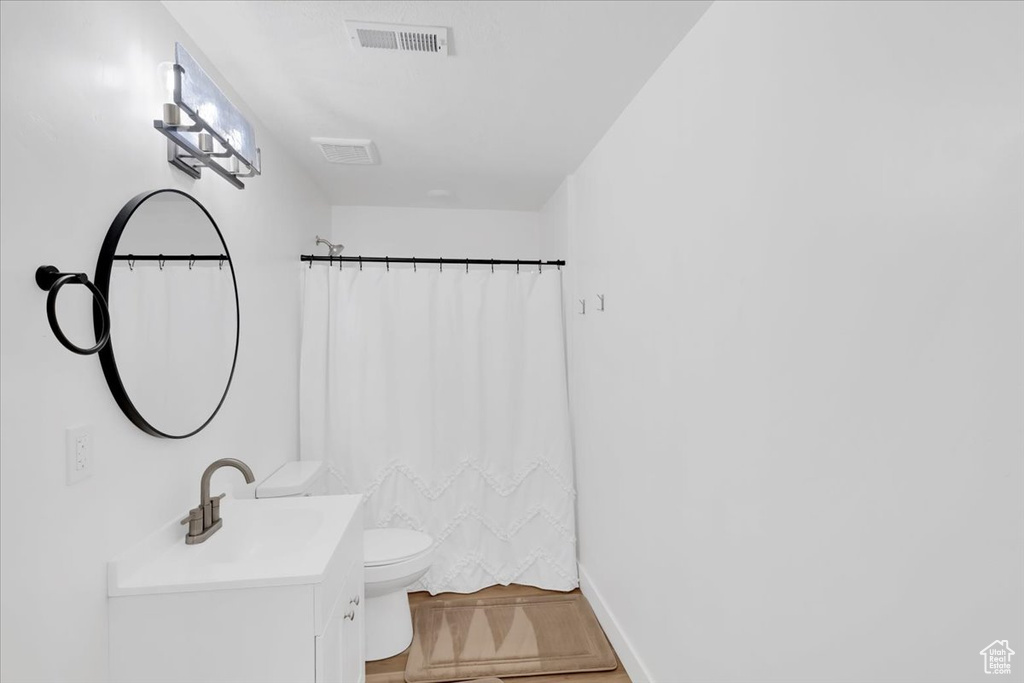 Bathroom with vanity, toilet, wood-type flooring, and a shower with curtain