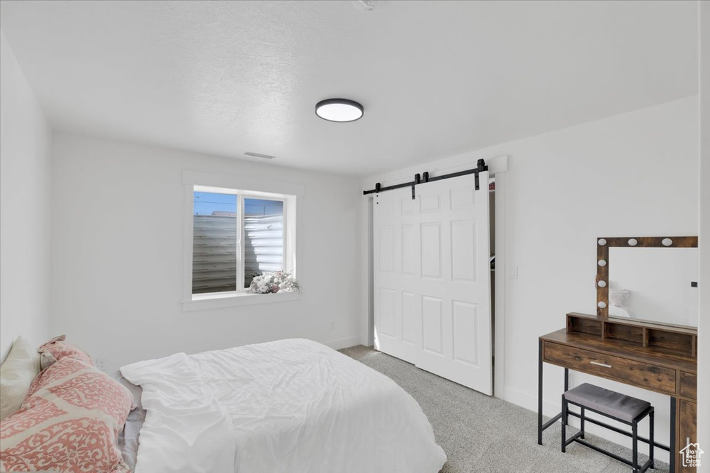 Bedroom featuring a barn door and carpet flooring