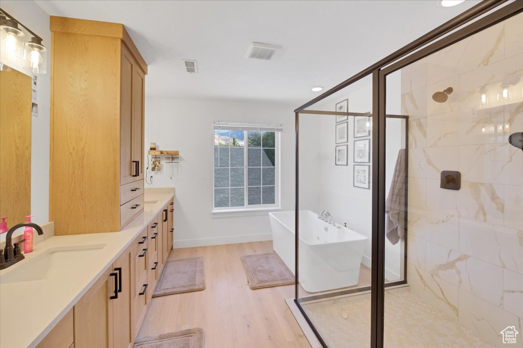 Bathroom featuring hardwood / wood-style floors, vanity, and independent shower and bath