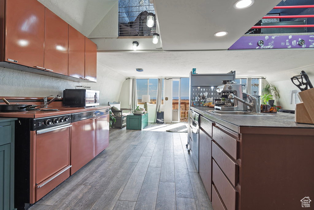 Kitchen featuring dishwasher, hardwood / wood-style flooring, range, and sink