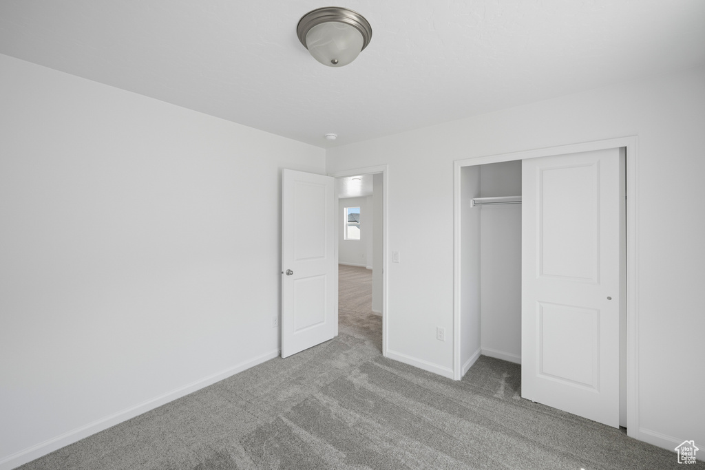 Unfurnished bedroom featuring light carpet and a closet