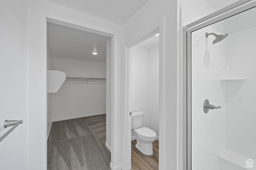 Bathroom featuring toilet, hardwood / wood-style floors, and a shower with shower door