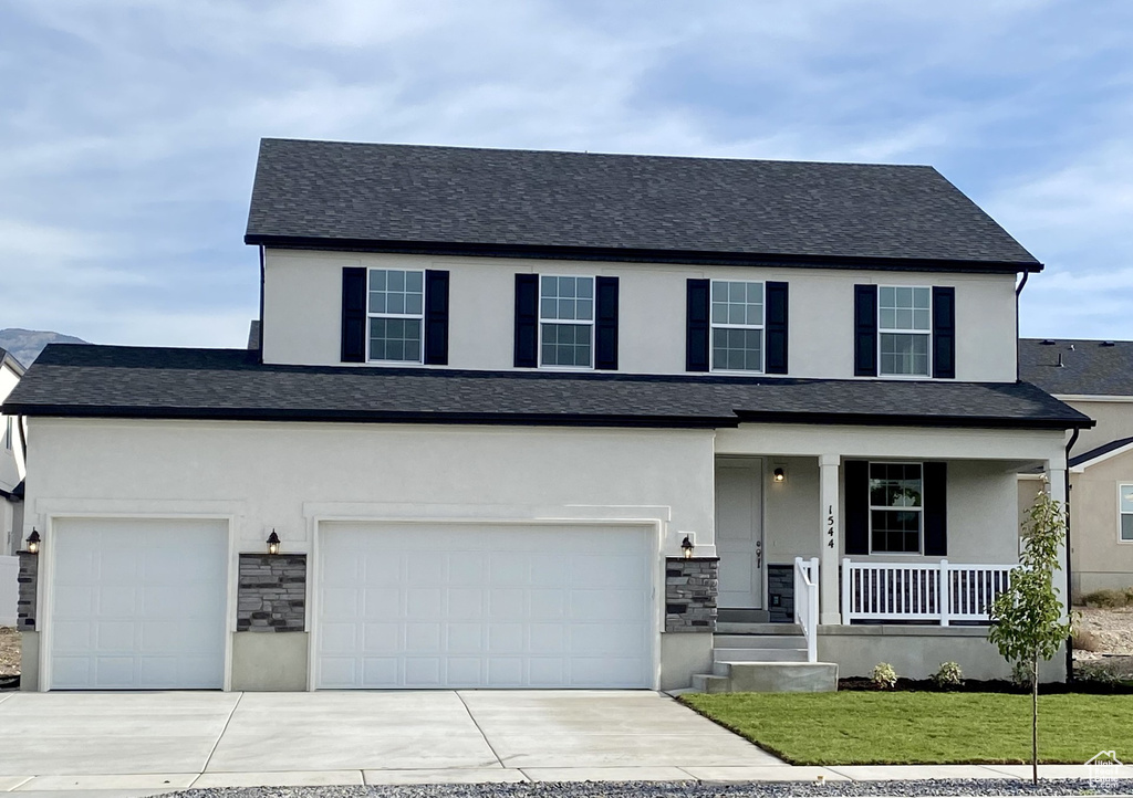 View of front of house with a front yard, a garage, and a porch