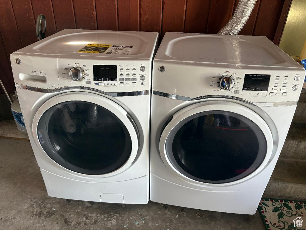 Clothes washing area with washer and clothes dryer and wood walls