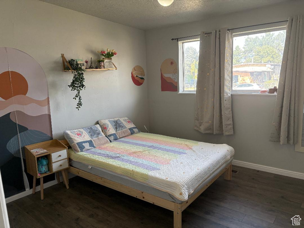 Bedroom with a textured ceiling and dark wood-type flooring