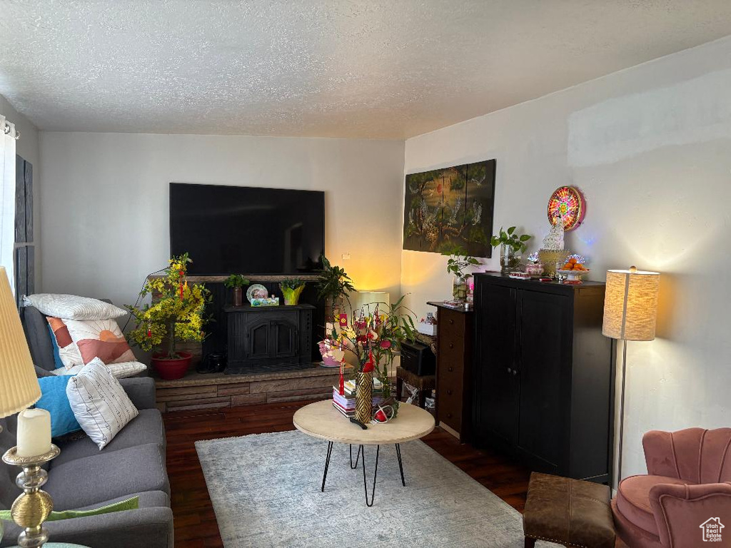 Living room featuring a textured ceiling, dark hardwood / wood-style floors, and a wood stove