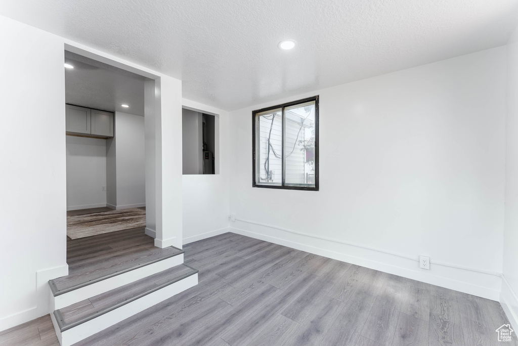 Empty room with a textured ceiling and light hardwood / wood-style floors