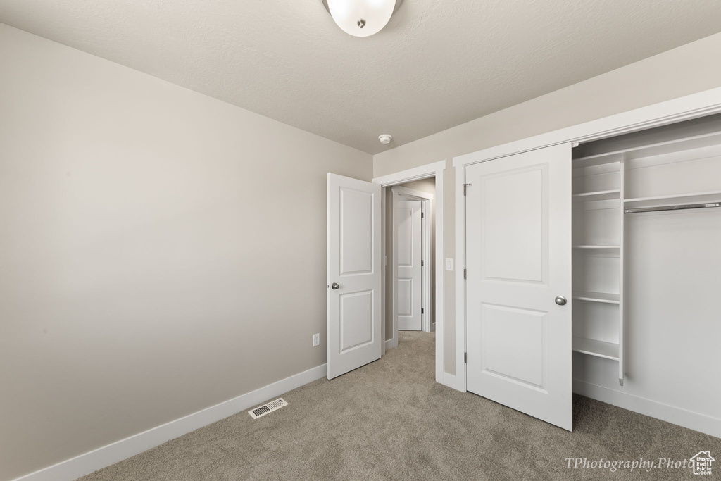 Unfurnished bedroom featuring light carpet and a closet