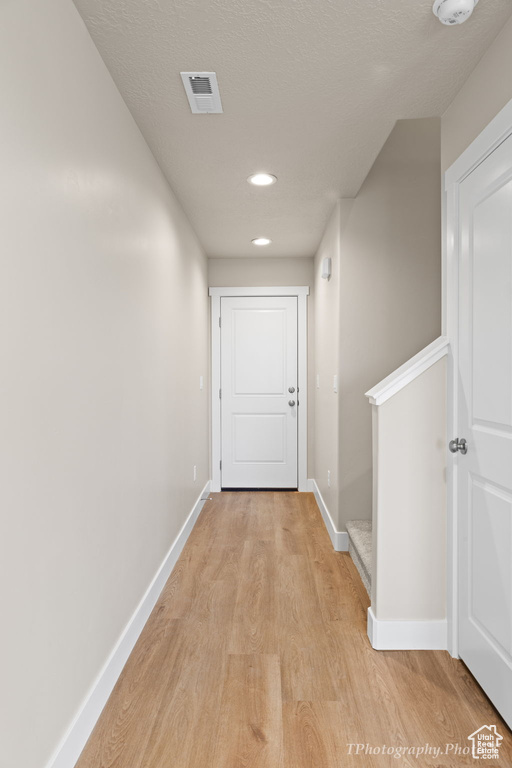 Hall with light hardwood / wood-style floors and a textured ceiling