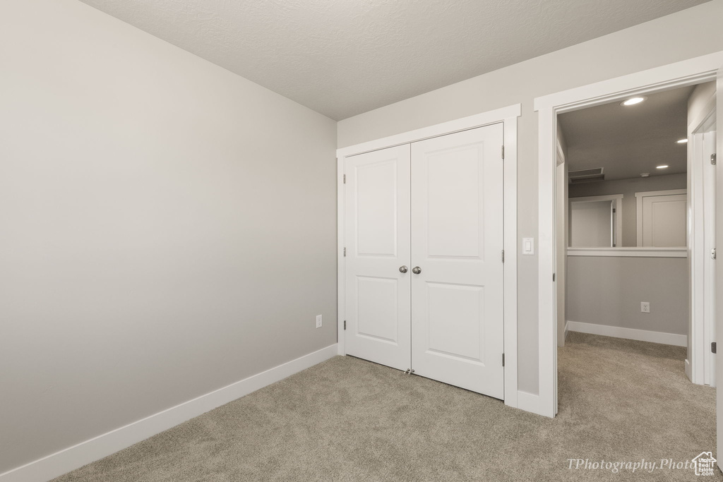 Unfurnished bedroom featuring a closet and light colored carpet