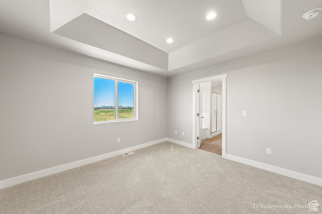 Carpeted empty room featuring a tray ceiling