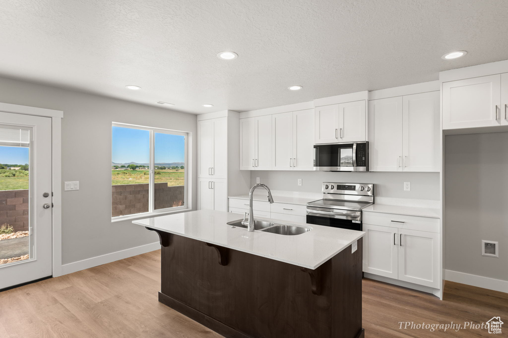 Kitchen with plenty of natural light, white cabinets, appliances with stainless steel finishes, and sink