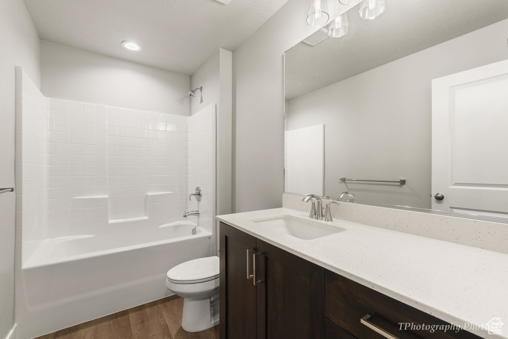 Full bathroom featuring hardwood / wood-style floors, shower / washtub combination, vanity, and toilet