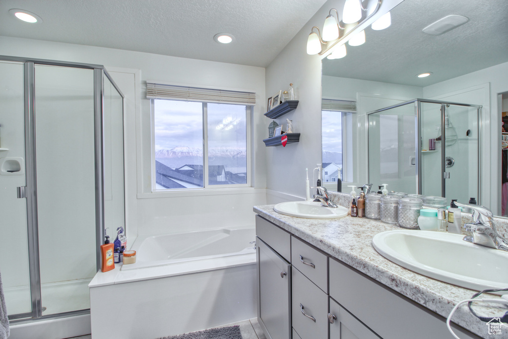 Bathroom featuring plenty of natural light, plus walk in shower, vanity, and a textured ceiling