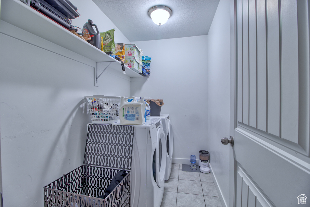 Laundry room with washer and clothes dryer, light tile patterned floors, and a textured ceiling