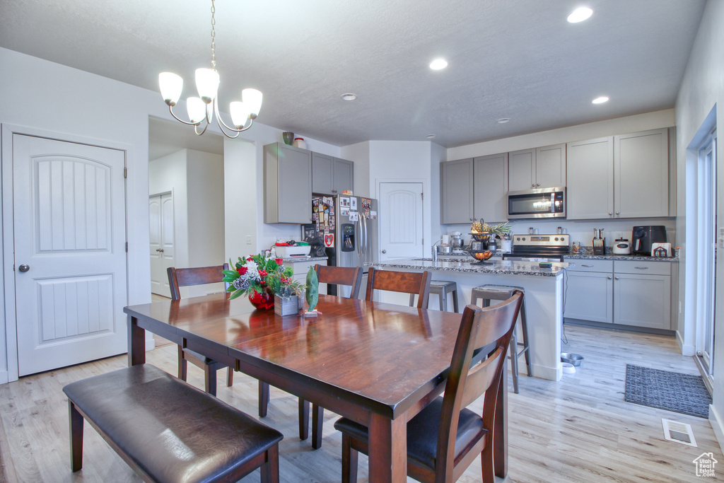 Dining space with light wood-type flooring and an inviting chandelier