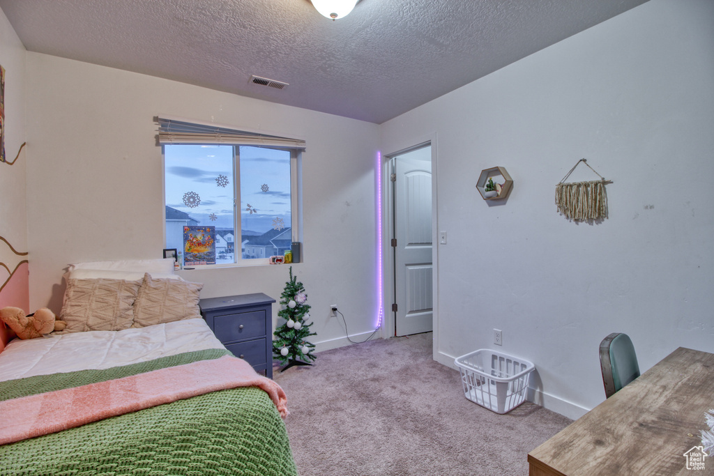 Bedroom with light colored carpet and a textured ceiling