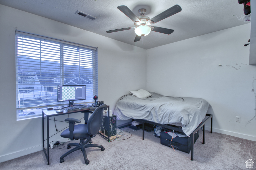 Carpeted bedroom featuring ceiling fan and a textured ceiling