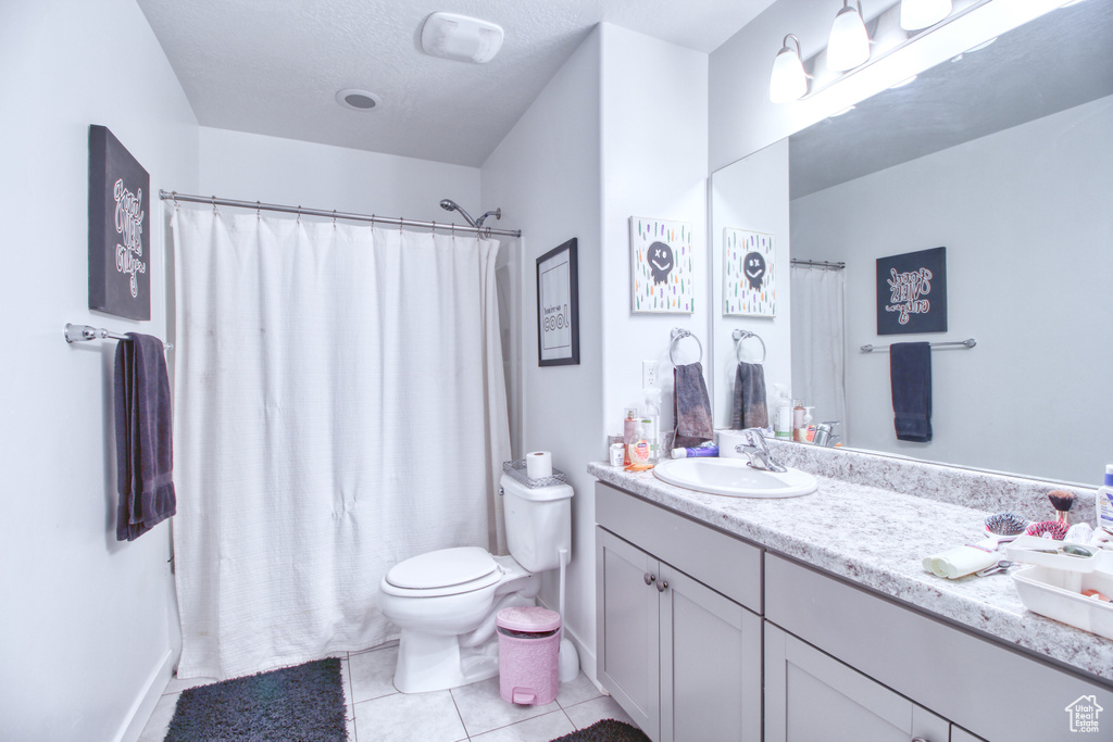 Bathroom featuring vanity, tile patterned flooring, and toilet