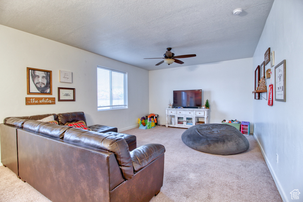 Carpeted living room featuring a textured ceiling and ceiling fan