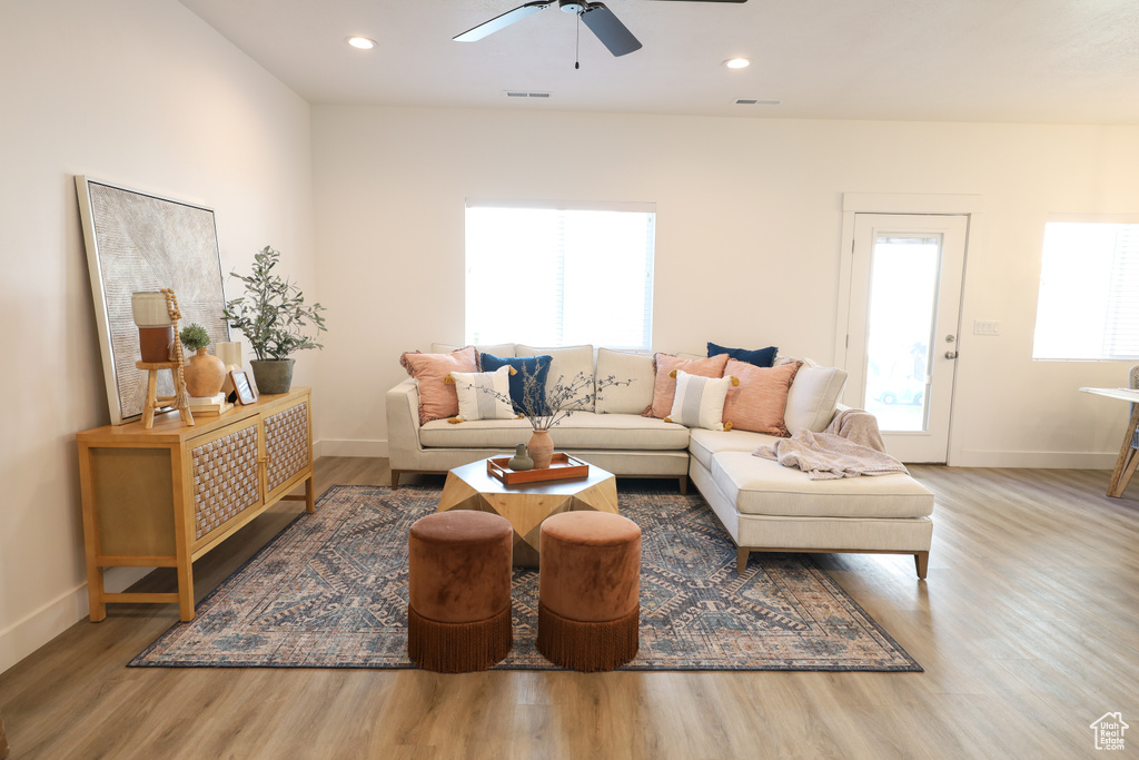 Living room with ceiling fan, light wood-type flooring, and plenty of natural light