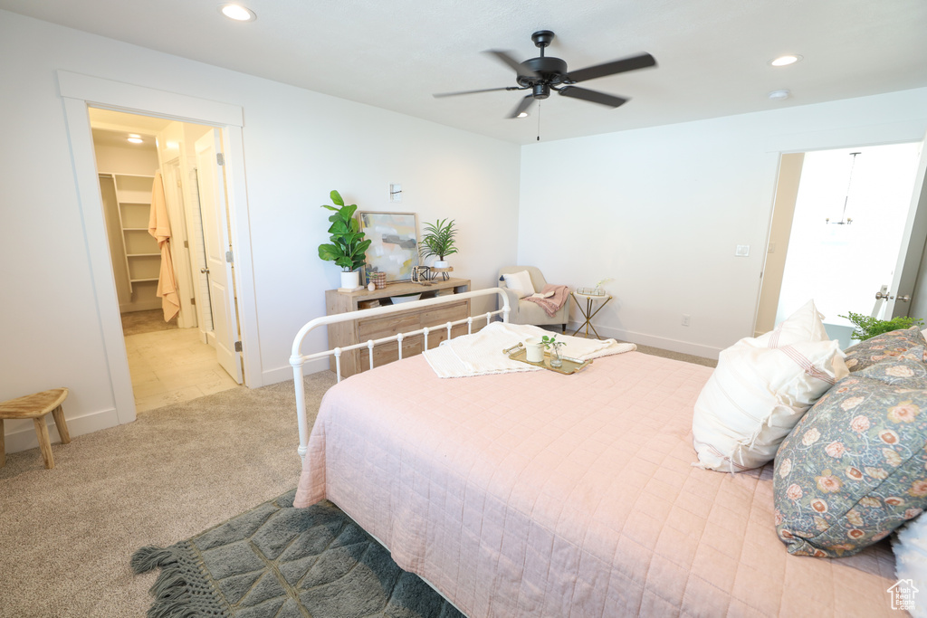 Carpeted bedroom featuring ceiling fan, a closet, and a walk in closet