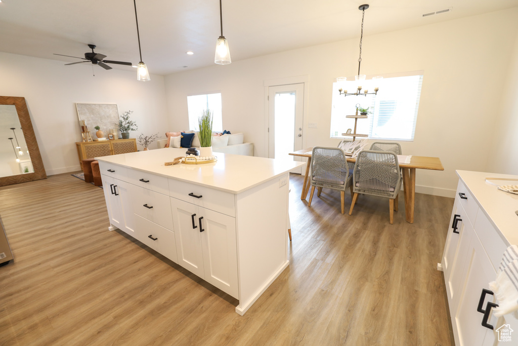 Kitchen with pendant lighting, a healthy amount of sunlight, light hardwood / wood-style floors, and white cabinets