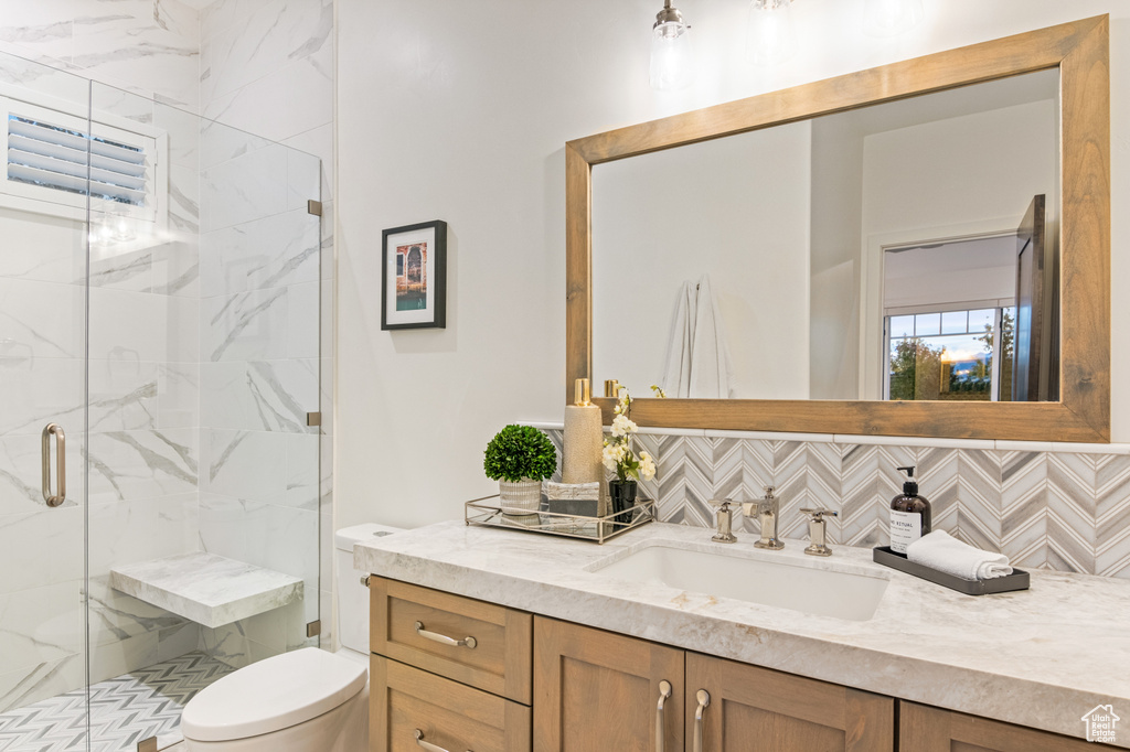 Bathroom with tasteful backsplash, an enclosed shower, vanity, and toilet