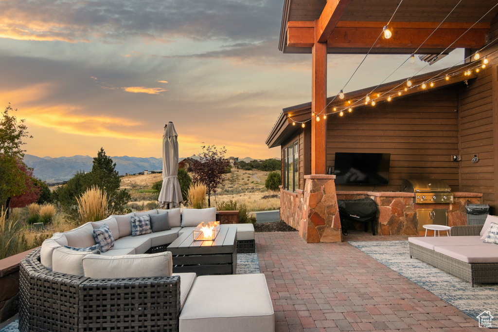 Patio terrace at dusk with an outdoor living space, a mountain view, and a grill