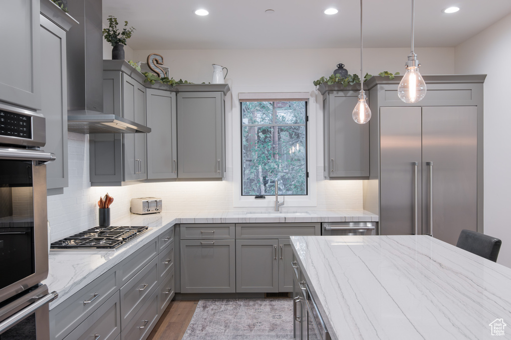 Kitchen featuring gray cabinets, light stone counters, decorative light fixtures, and stainless steel appliances