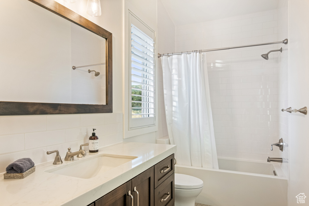 Full bathroom featuring backsplash, shower / bathtub combination with curtain, vanity, and toilet