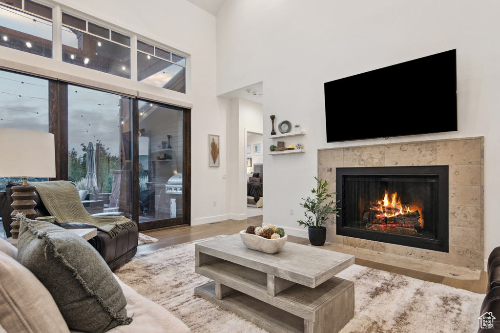 Living room with a towering ceiling, hardwood / wood-style floors, and a tile fireplace