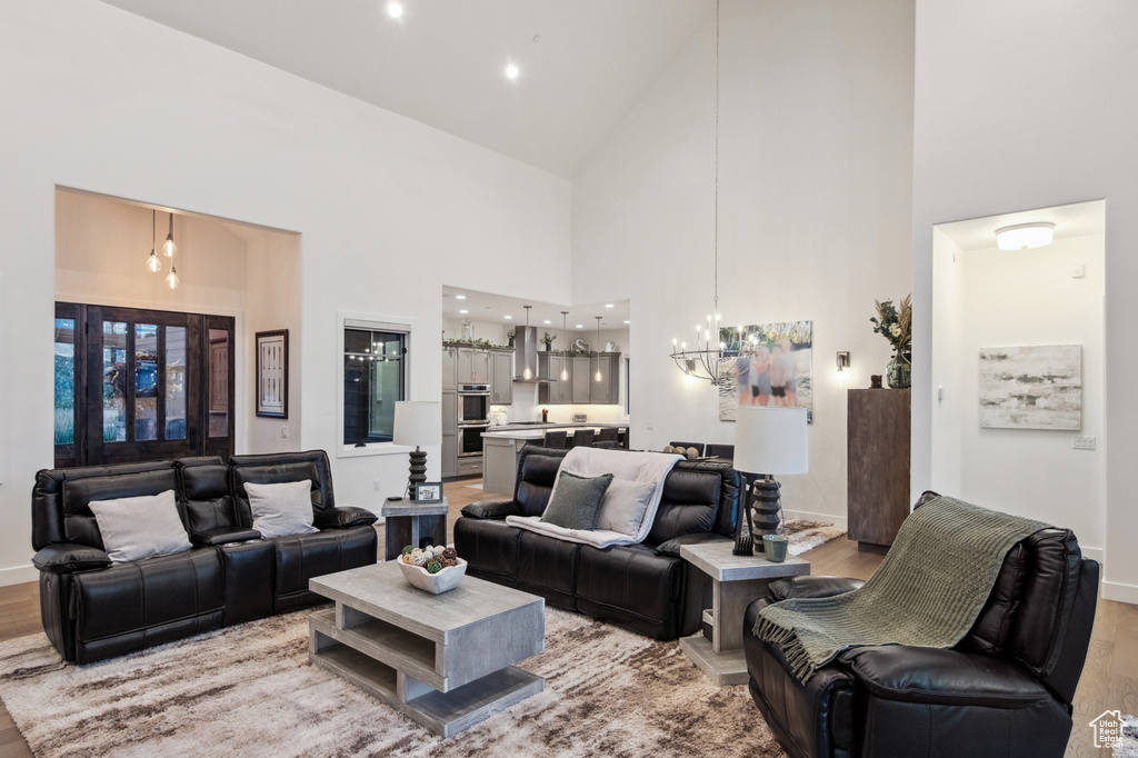 Living room with light hardwood / wood-style floors, high vaulted ceiling, and an inviting chandelier