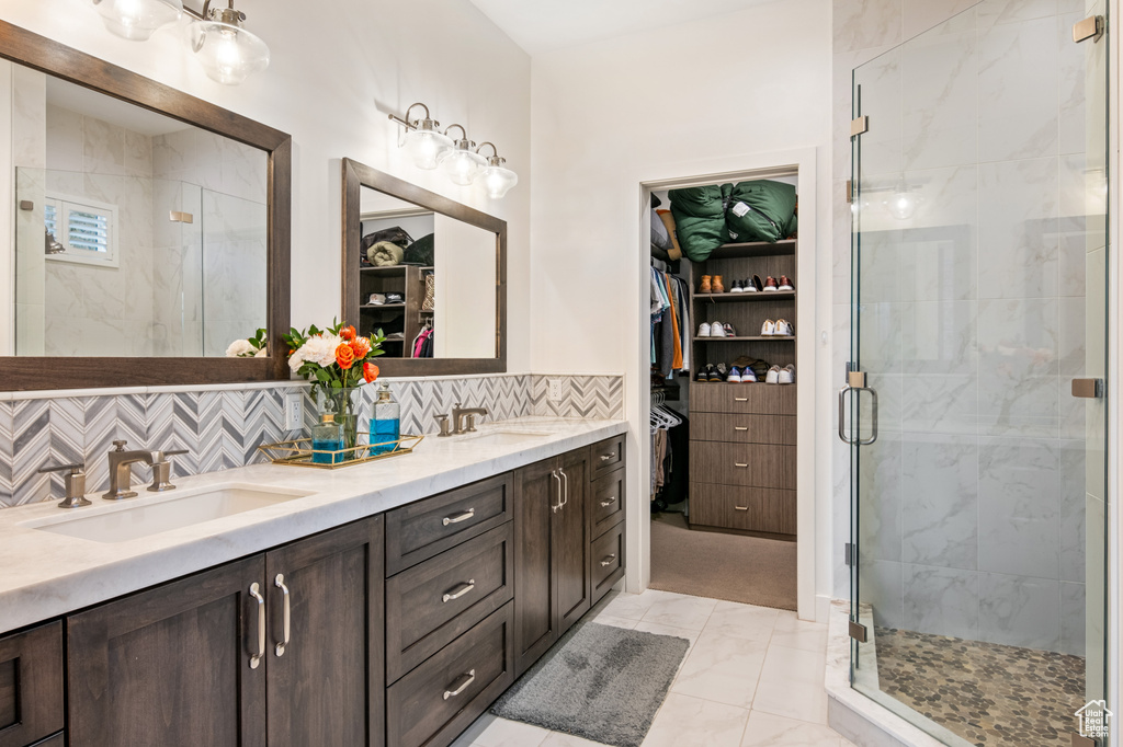 Bathroom featuring tasteful backsplash, a shower with door, and vanity