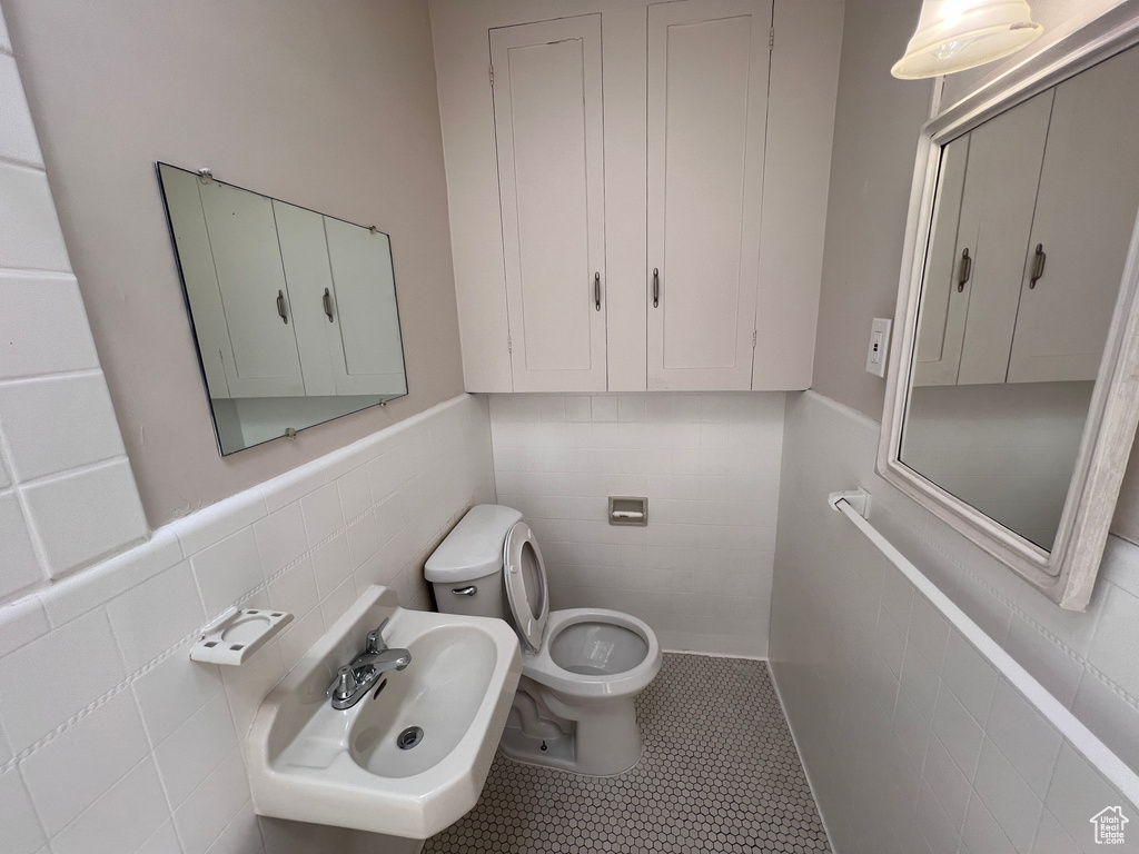 Bathroom with tile walls, tile patterned floors, sink, and toilet