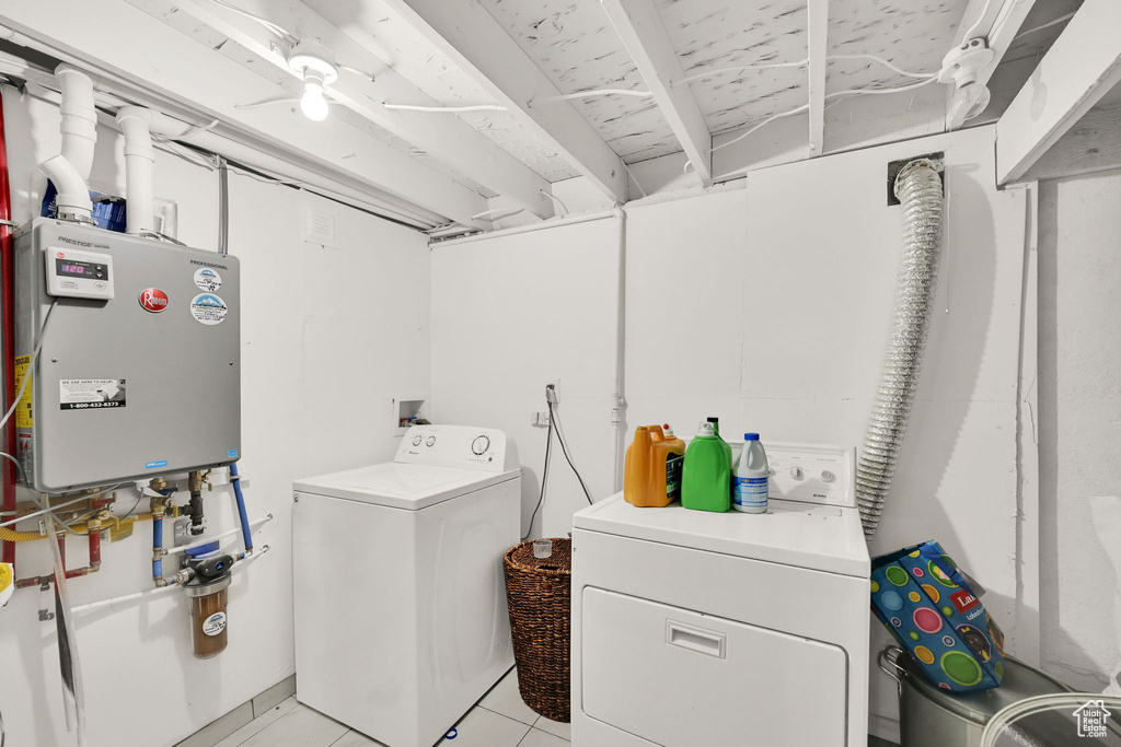 Laundry room with washing machine and dryer, light tile patterned floors, and tankless water heater