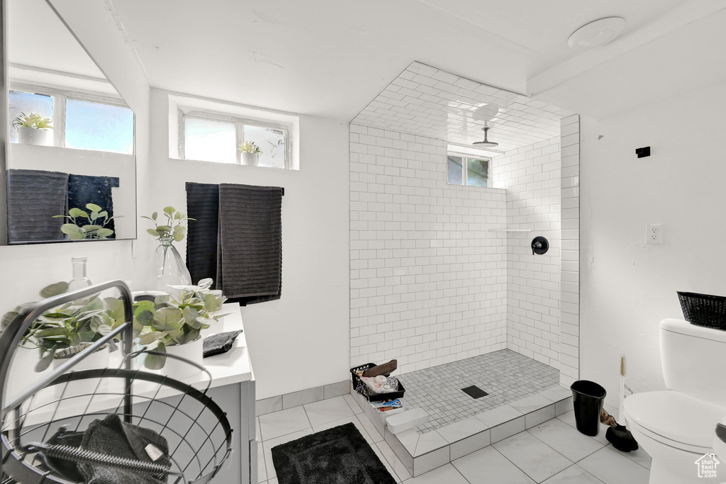 Bathroom featuring vanity, tile patterned floors, toilet, and tiled shower