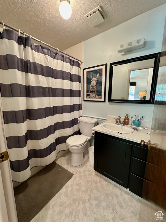 Bathroom with toilet, vanity, a shower with shower curtain, and a textured ceiling