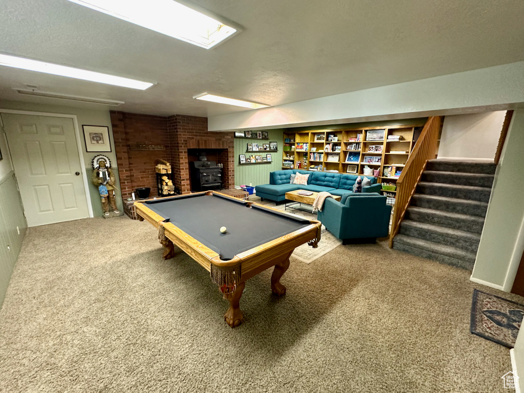 Rec room featuring carpet floors, a textured ceiling, billiards, and a wood stove