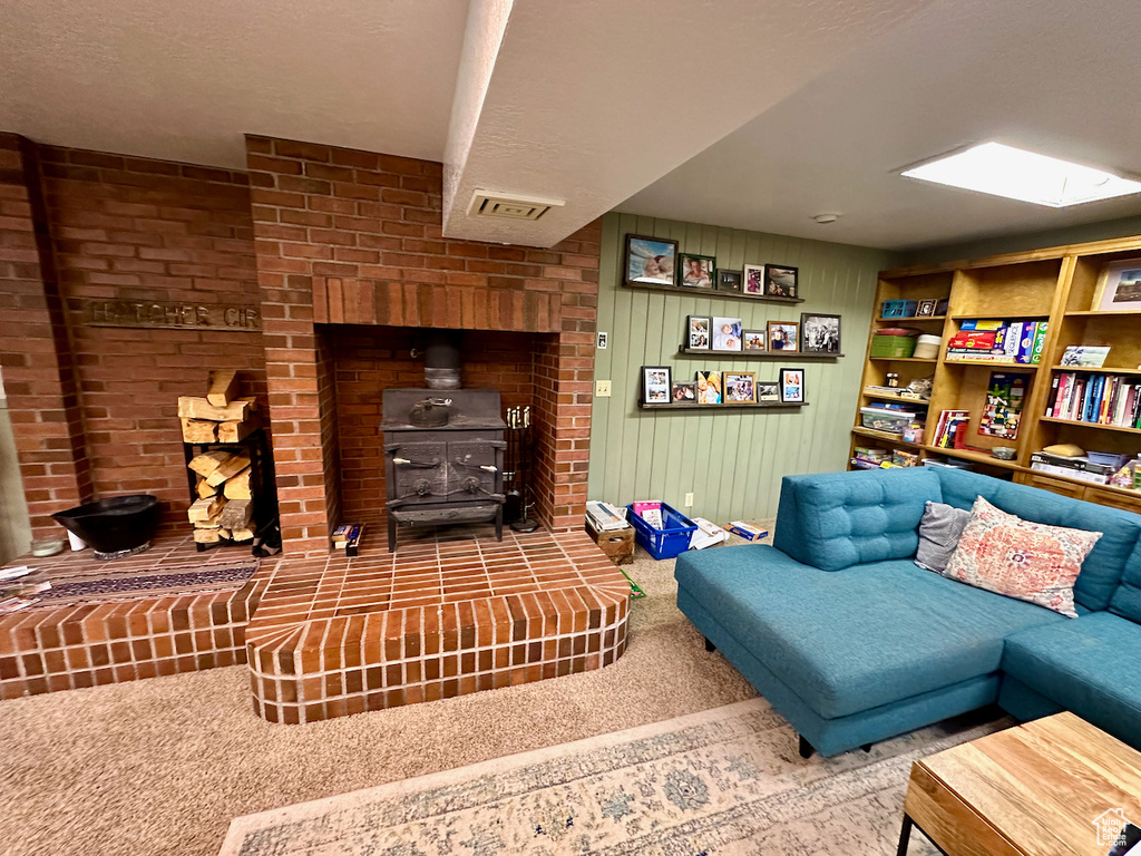 Living room with wooden walls, a wood stove, carpet floors, a skylight, and a textured ceiling