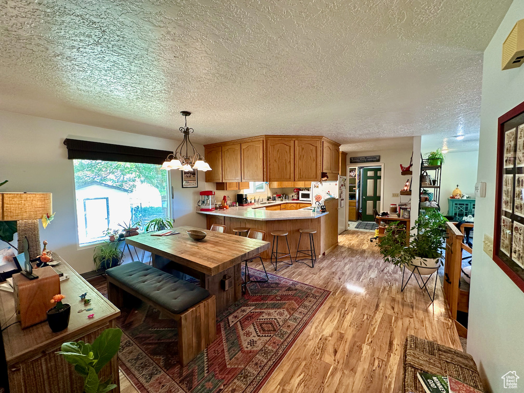 Dining room with light hardwood / wood-style floors, an inviting chandelier, and a textured ceiling