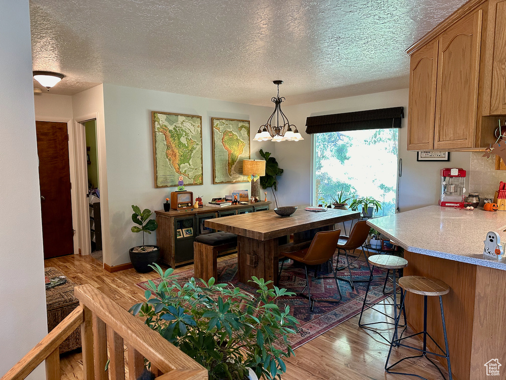 Dining area featuring an inviting chandelier, light hardwood / wood-style flooring, and a textured ceiling