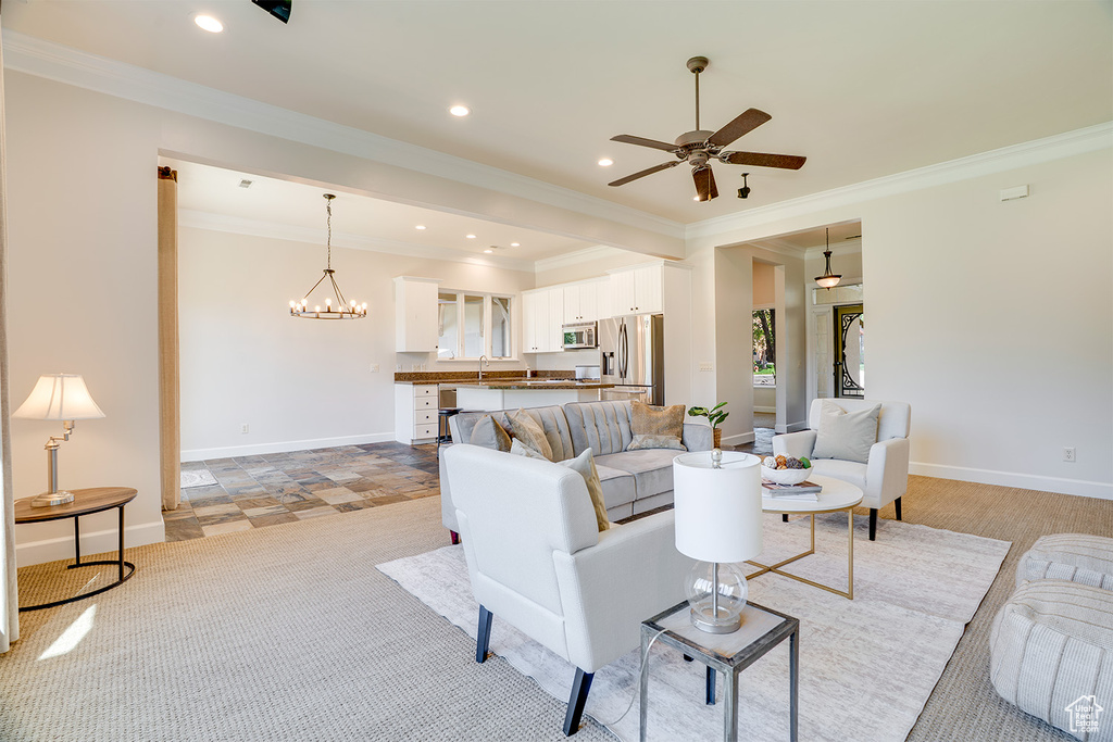 Living room with ornamental molding, ceiling fan, baseboards, recessed lighting, and a chandelier