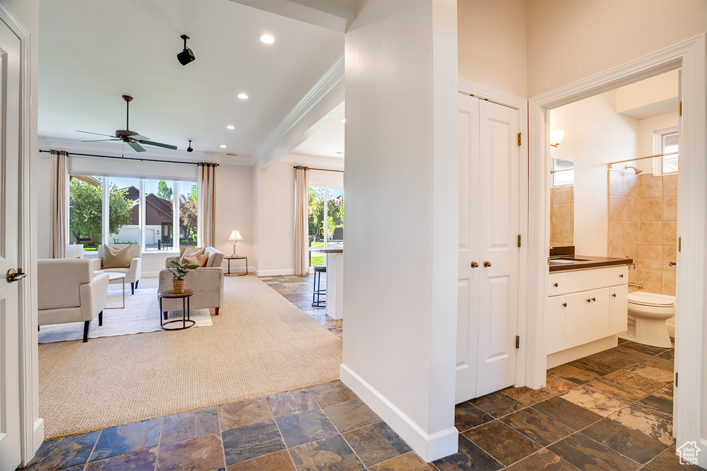 Hallway featuring plenty of natural light, ornamental molding, baseboards, stone tile flooring, and recessed lighting