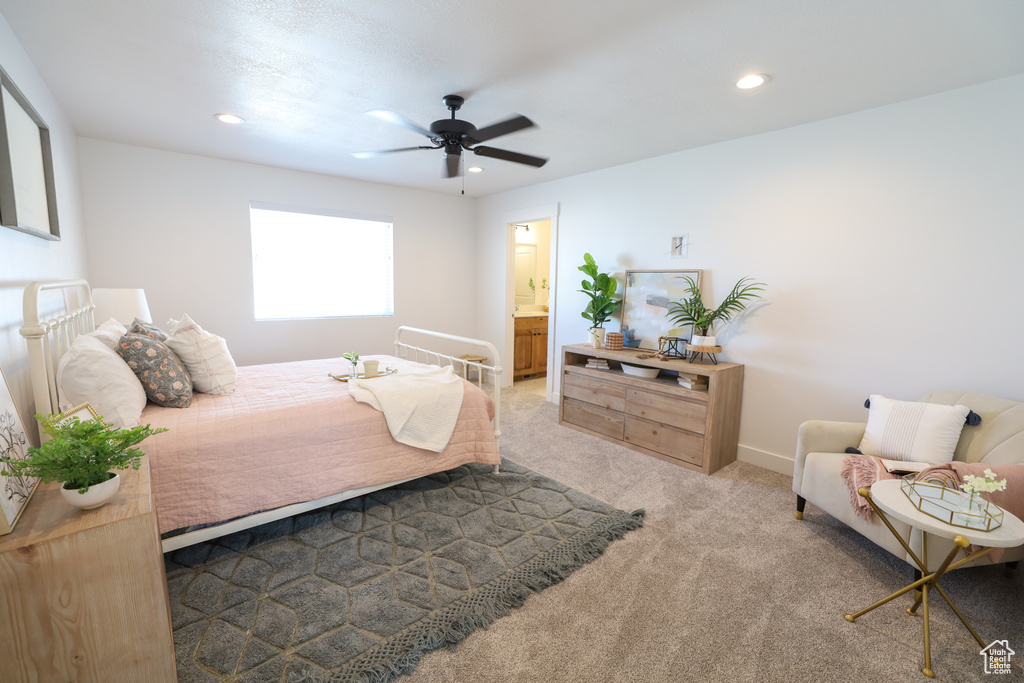 Bedroom with ceiling fan, connected bathroom, and light carpet