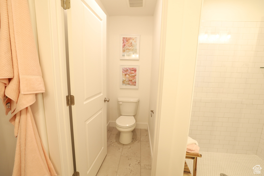 Bathroom with tile patterned flooring, tiled shower, and toilet